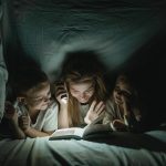 Mom reading a book with her kids under the covers, safe from bed bugs and other pests that cause health risk